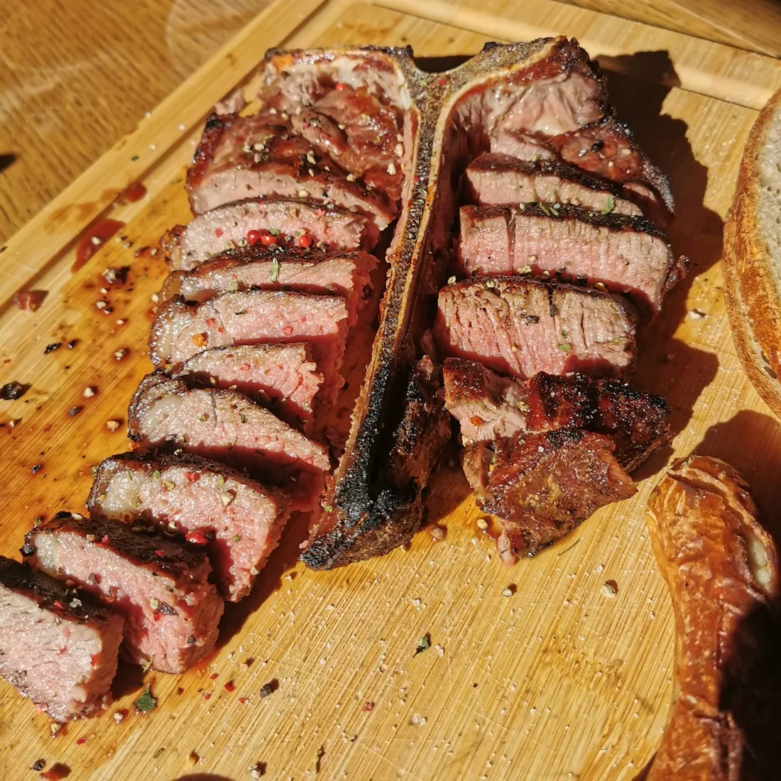 Rosa gebratenes Porterhouse-Steak in Scheiben entlang des Knochens auf einem Holzbrett