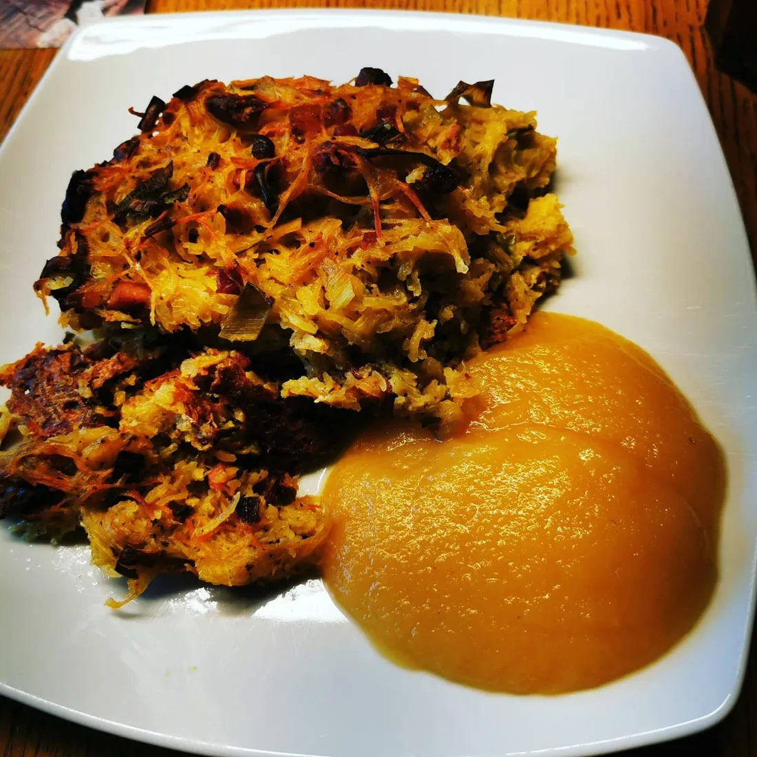 Gebräunter Schales aus geriebenen Kartoffeln mit Apfelmus auf einem weißen Teller