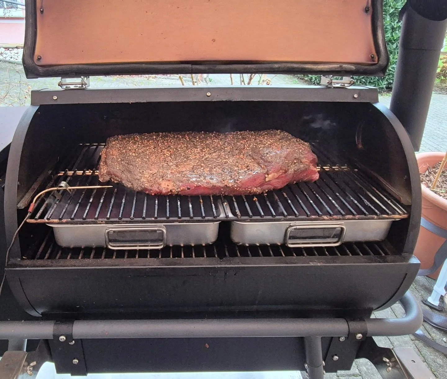 Gewürztes Brisket mit Temperaturfühler im geöffneten Smoker